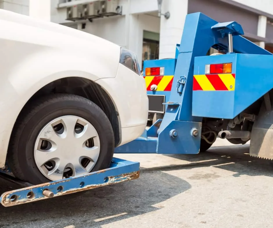 wheel-lift tow truck loading a sedan