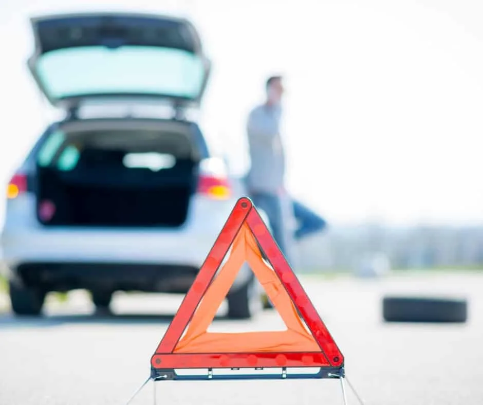 roadside warning triangle in front of a broken-down vehicle